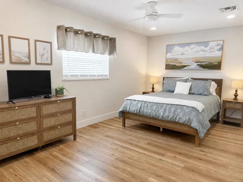 Brillante dormitorio inspirado en la costa con TV, ventilador de techo y ambiente relajante
