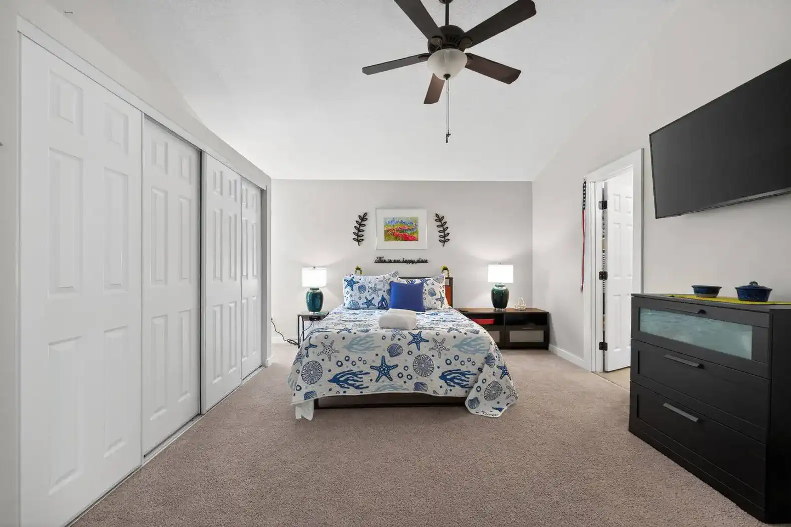 Cozy guest bedroom with a blue and white bedspread, closet space, and a TV