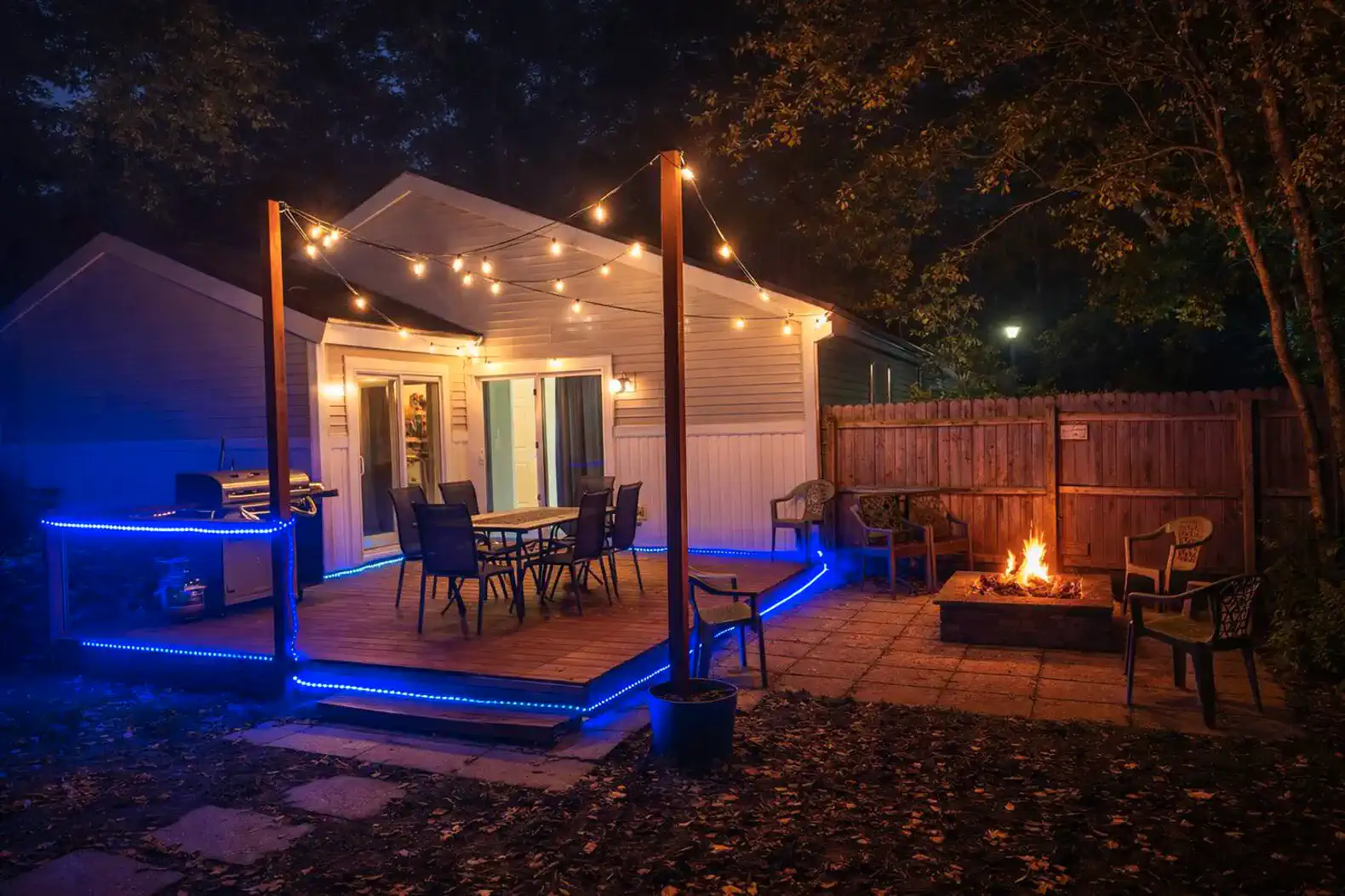 Cozy outdoor patio with string lights, dining area, and fire pit