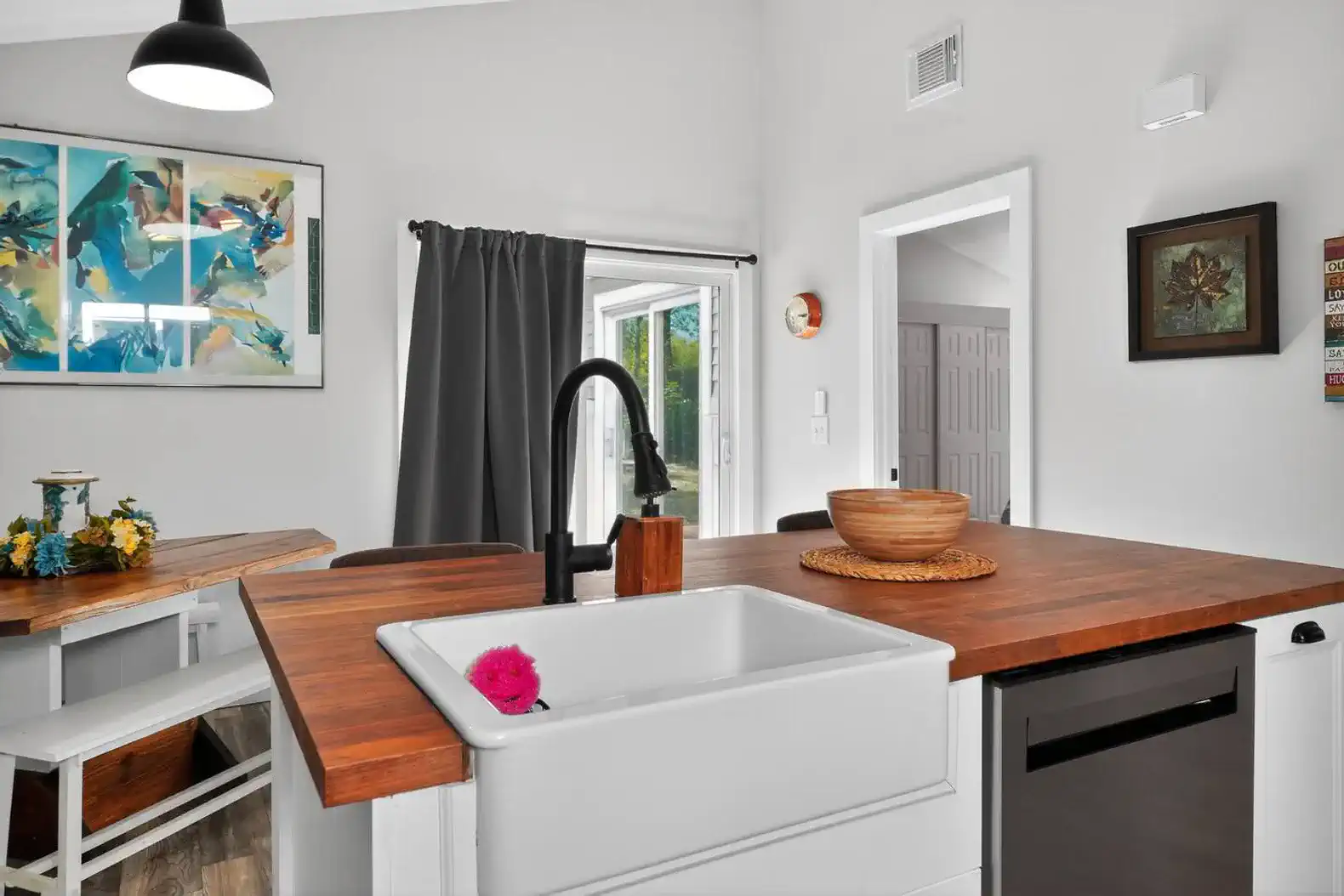 Bright kitchen with a farmhouse sink and wooden countertop, featuring modern decor and natural light