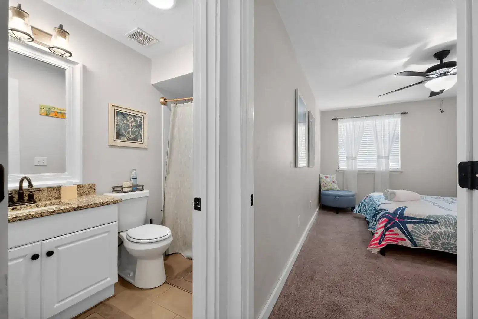 Bright bathroom with granite countertop and adjacent guest bedroom featuring a colorful quilt