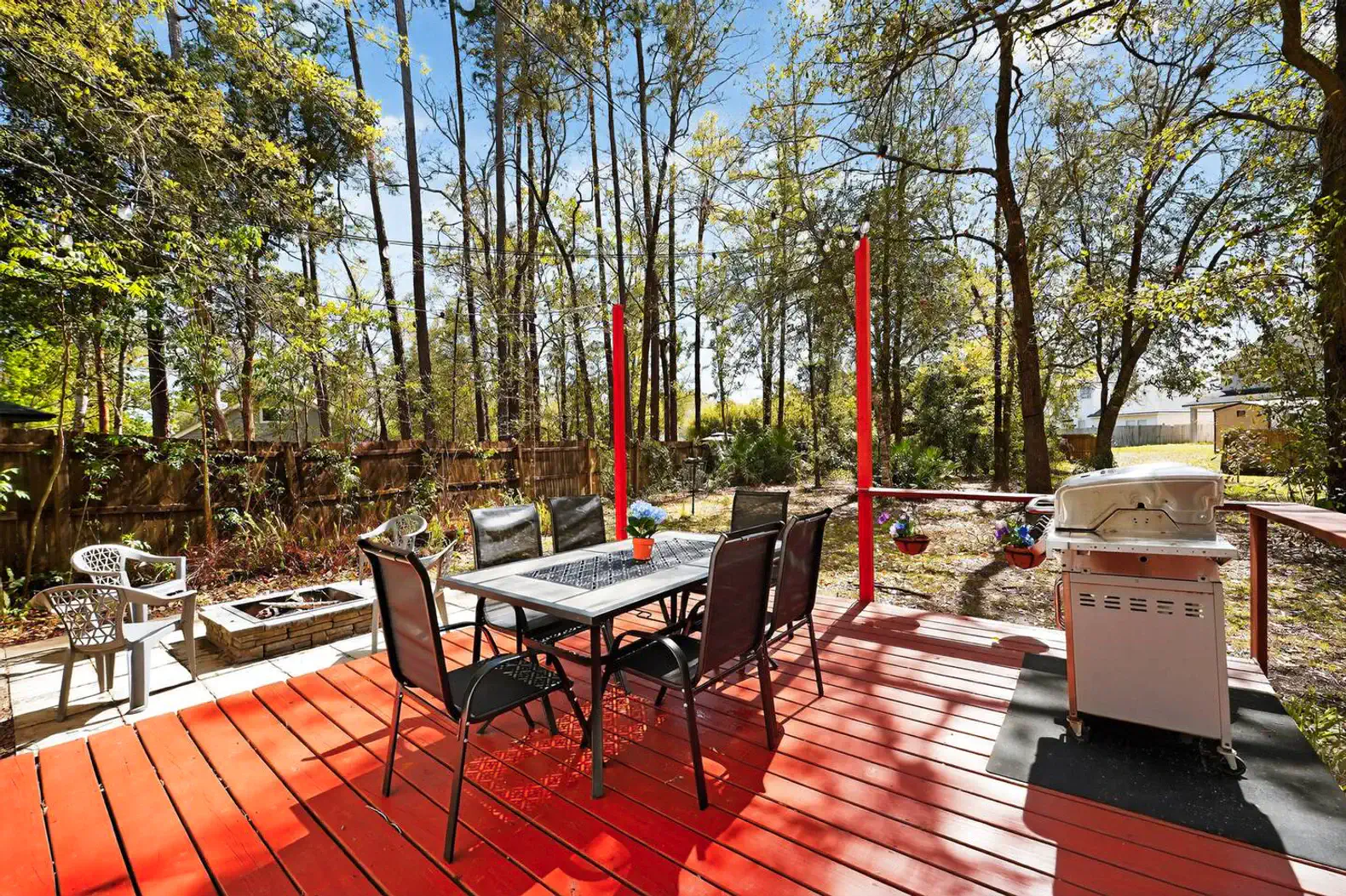 Spacious outdoor deck with dining table, BBQ grill, and surrounded by trees
