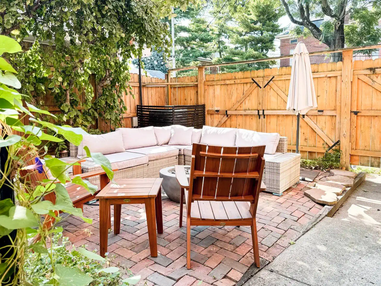 Cozy outdoor seating area with a sectional sofa and umbrella surrounded by wooden fencing