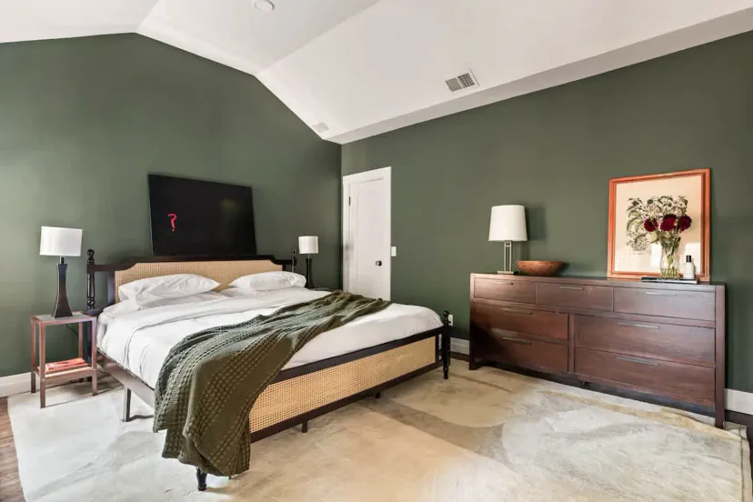 Spacious master bedroom with green walls and stylish furnishings