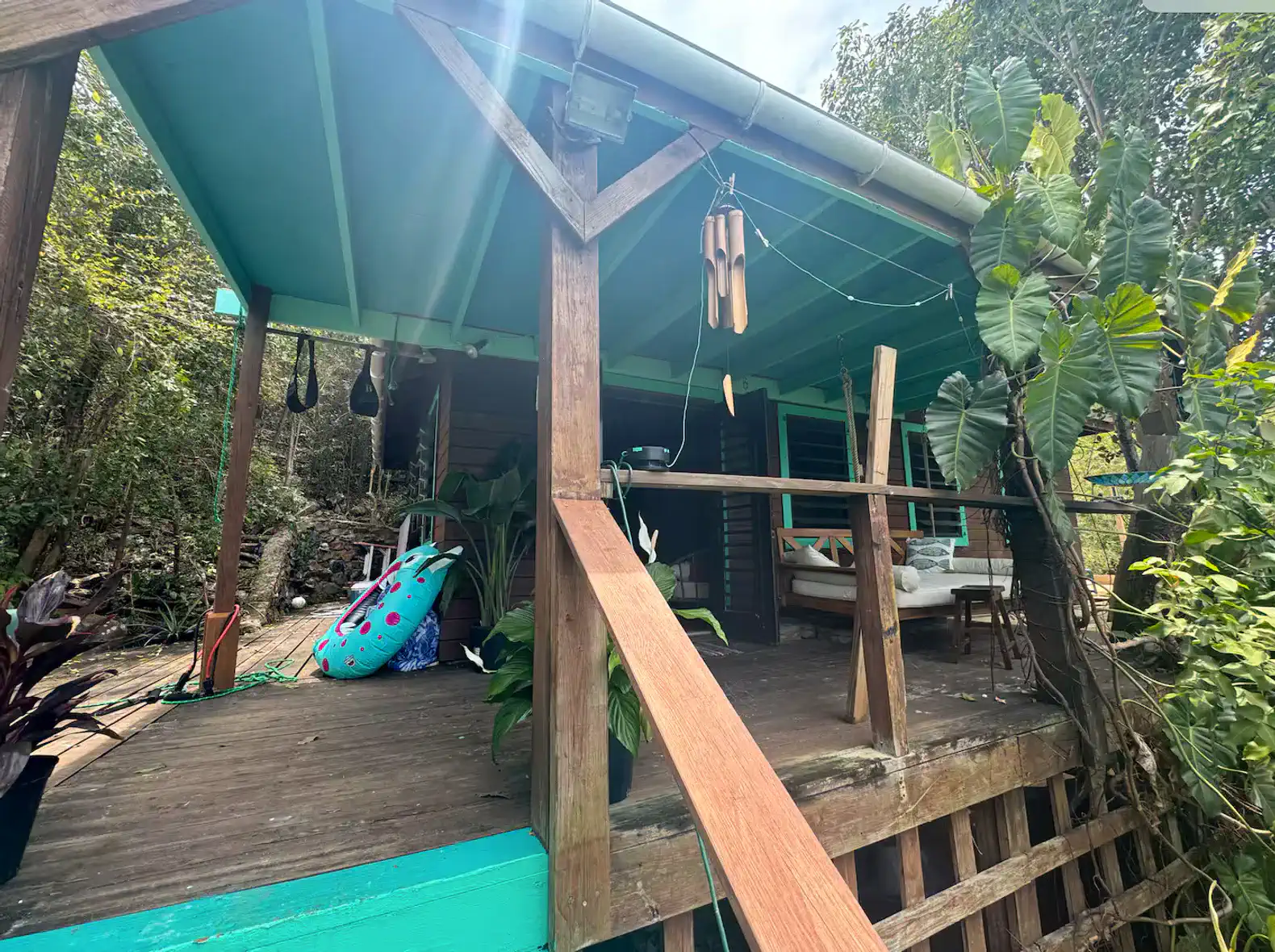 Spacious deck with colorful seating, tropical plants, and a hammock overlooking lush greenery