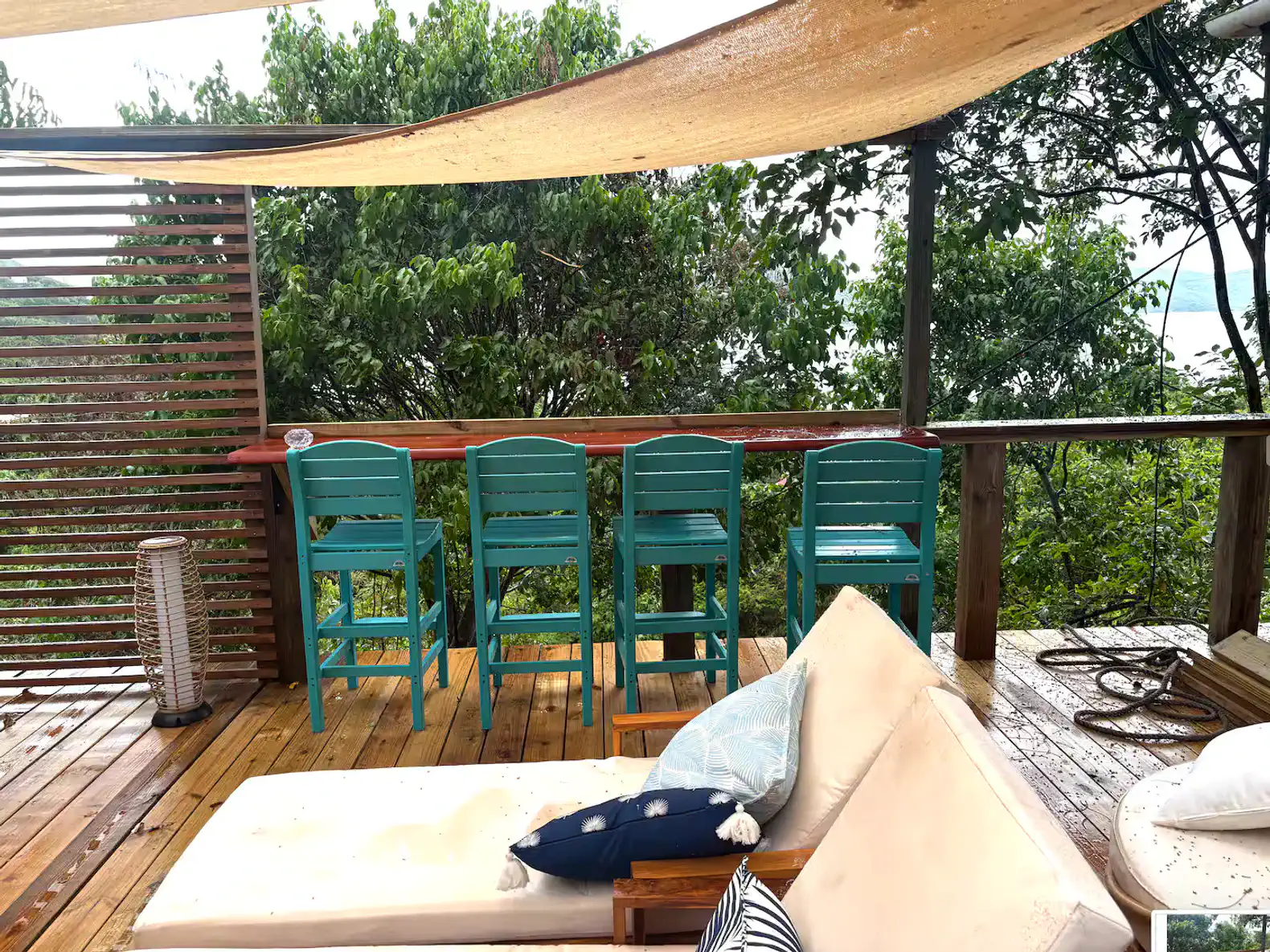 Cozy outdoor seating area with turquoise bar stools and a shaded view of lush greenery