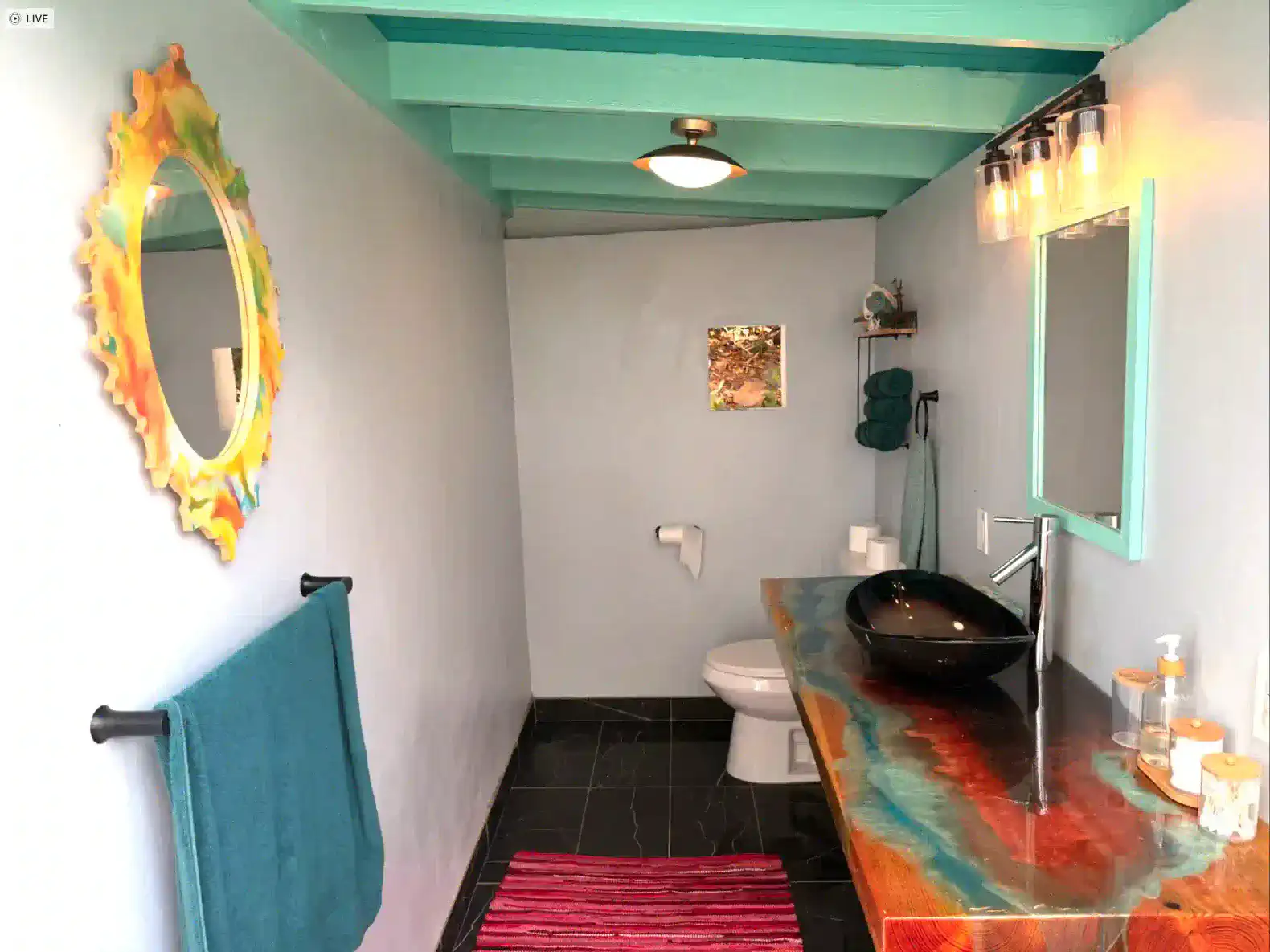 Stylish bathroom with a unique sink, colorful mirror, and modern decor
