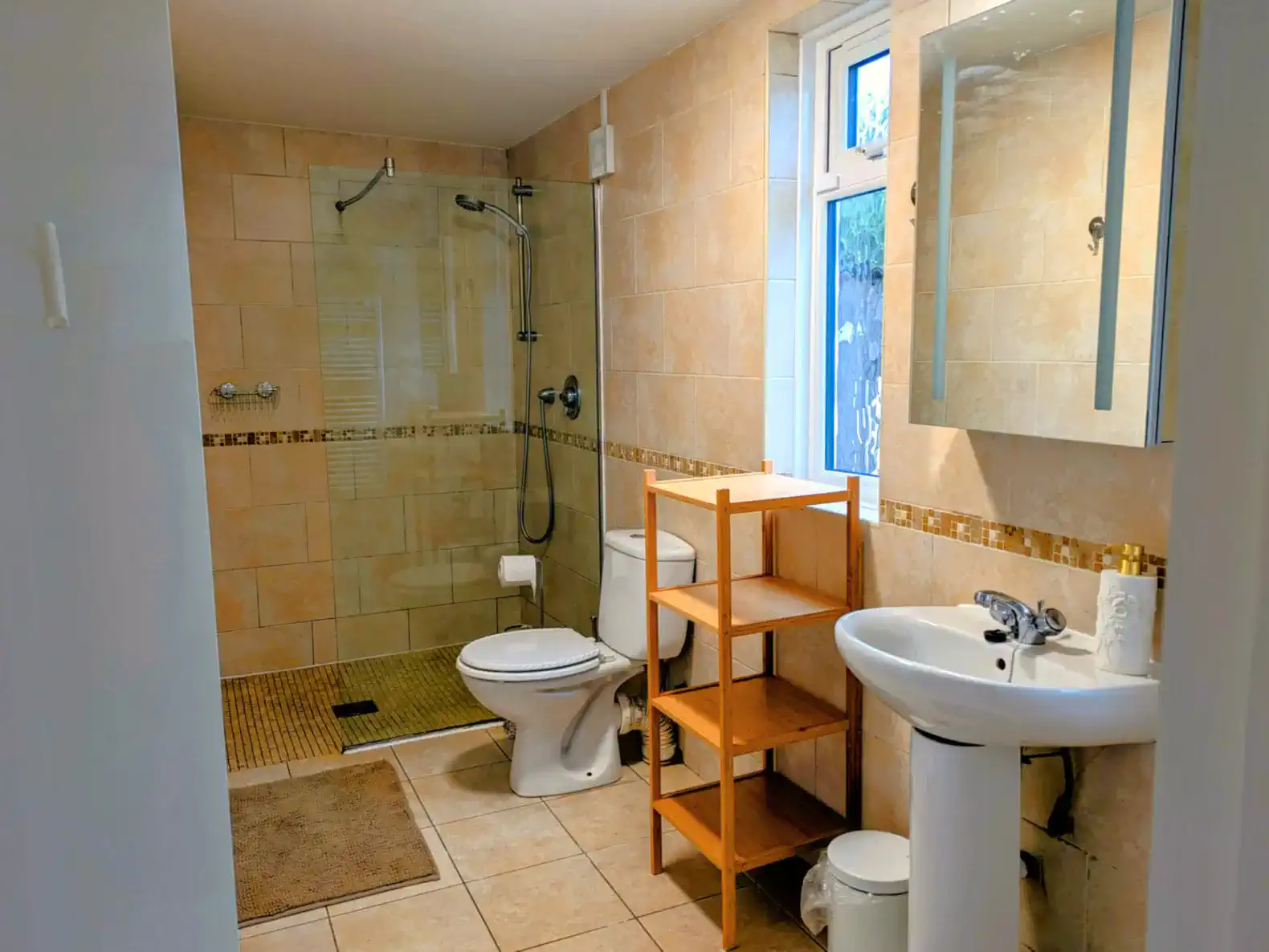 Spacious bathroom with shower, toilet, and wooden shelving unit