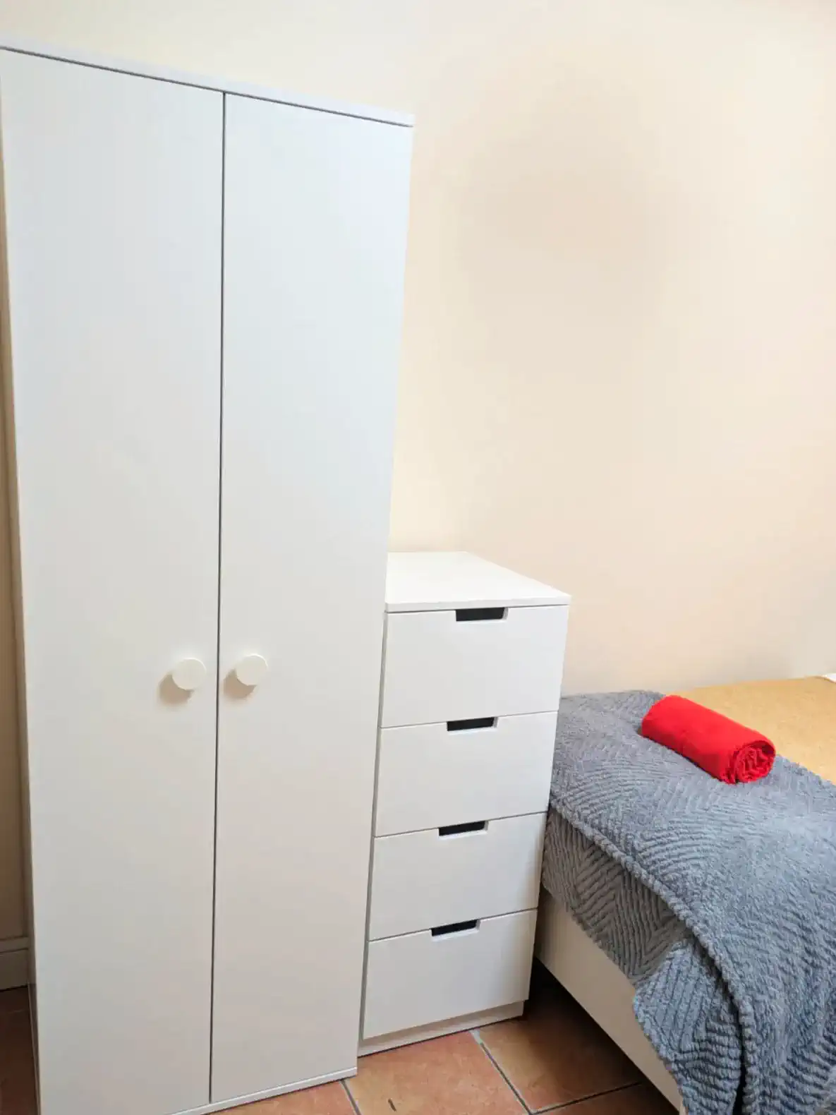 Minimalist bedroom storage with wardrobe and dresser beside a neatly made bed