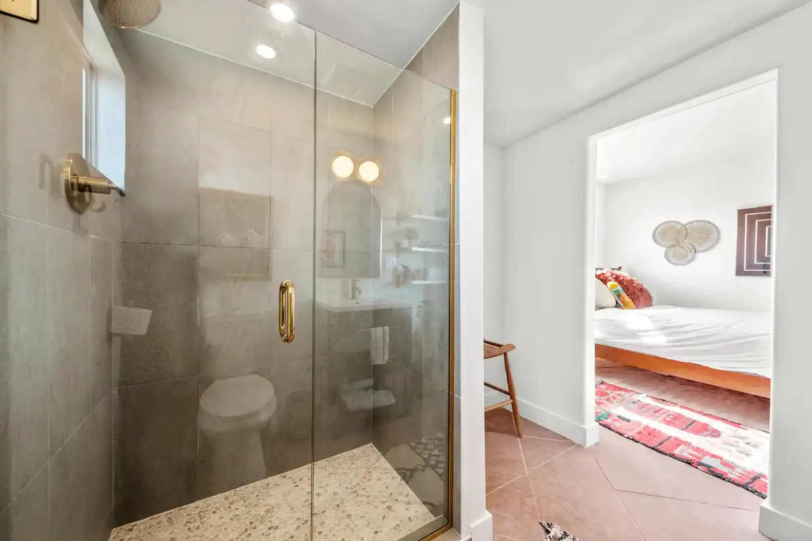 Ducha moderna con paredes de azulejos y detalles en dorado
