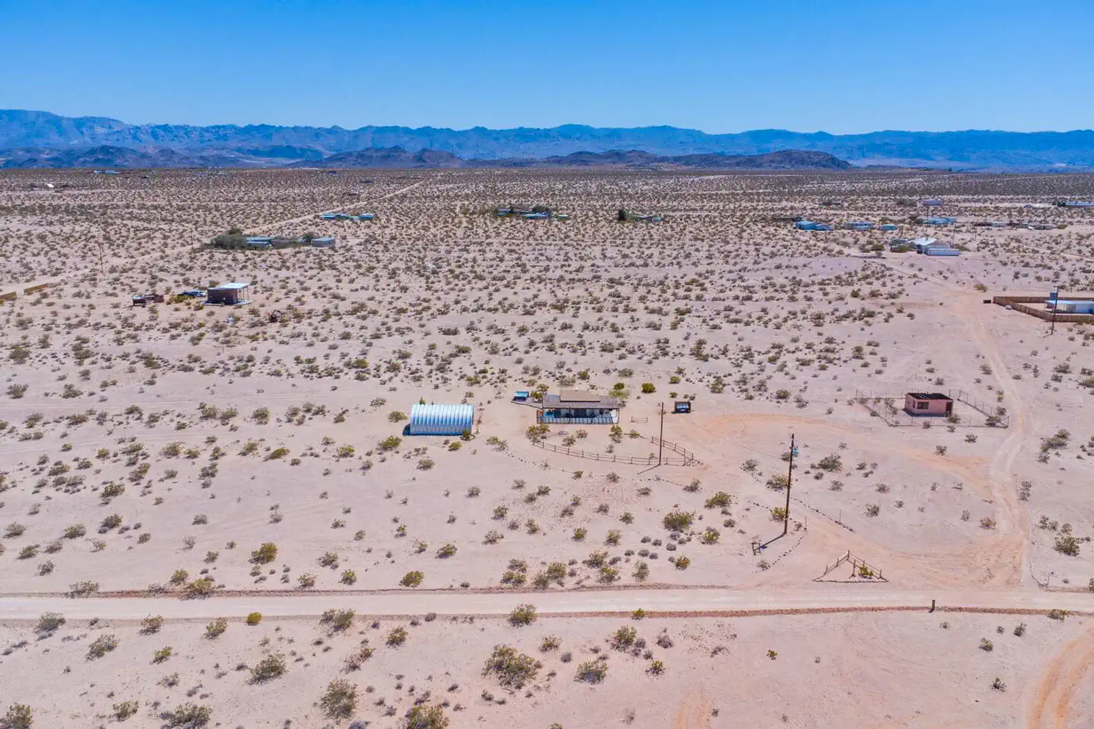 Aerial view of a desert landscape with sparse vegetation and distant mountains
