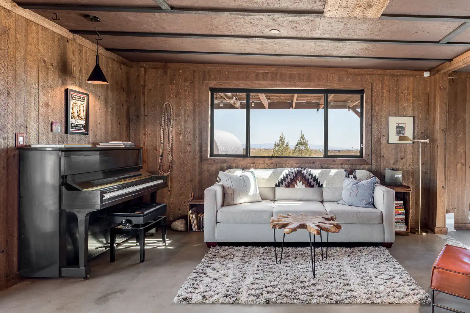 Cozy living room with a piano, modern sofa, and large window showcasing scenic views