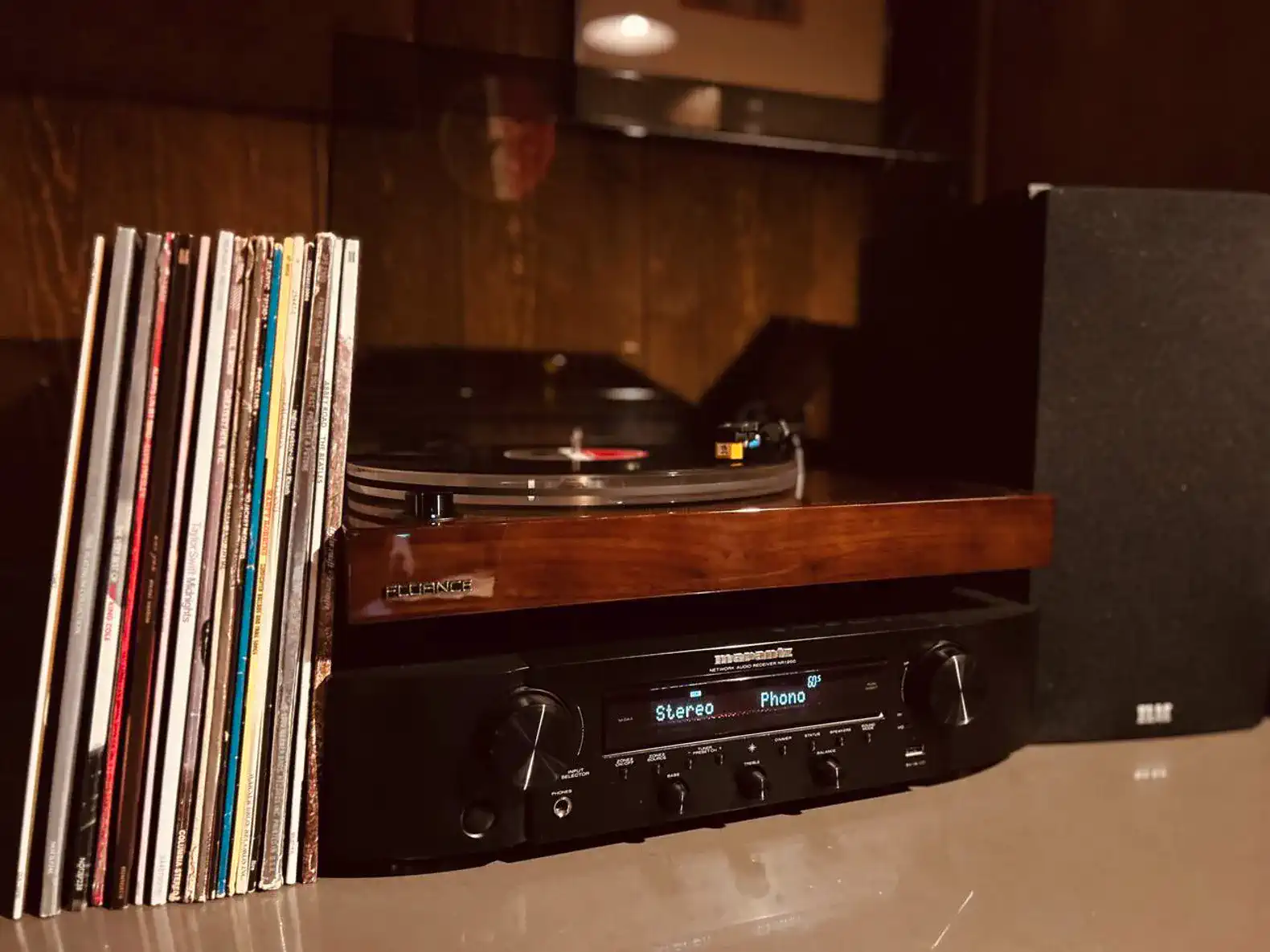 Vinyl records next to a turntable and audio equipment in a cozy setting