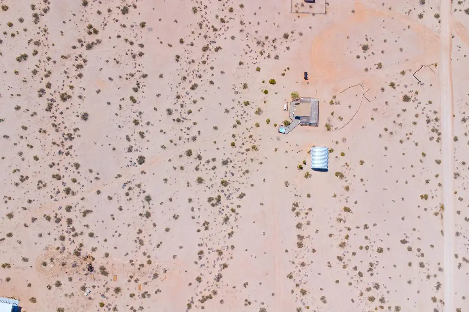 Aerial view of a desert property with sparse vegetation and a few structures
