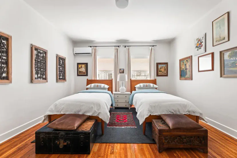 Bright guest bedroom with twin beds, artwork, and wooden accents