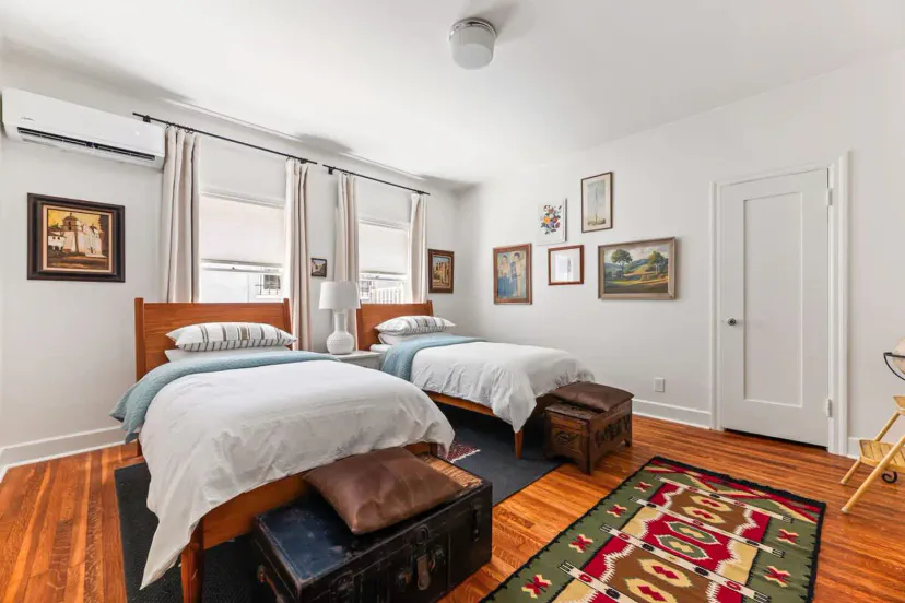Chambre d'amis lumineuse avec deux lits, des accents en bois et des œuvres d'art décoratives