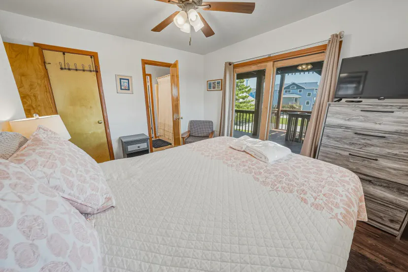 Cozy, sunlit bedroom with private balcony access and TV
