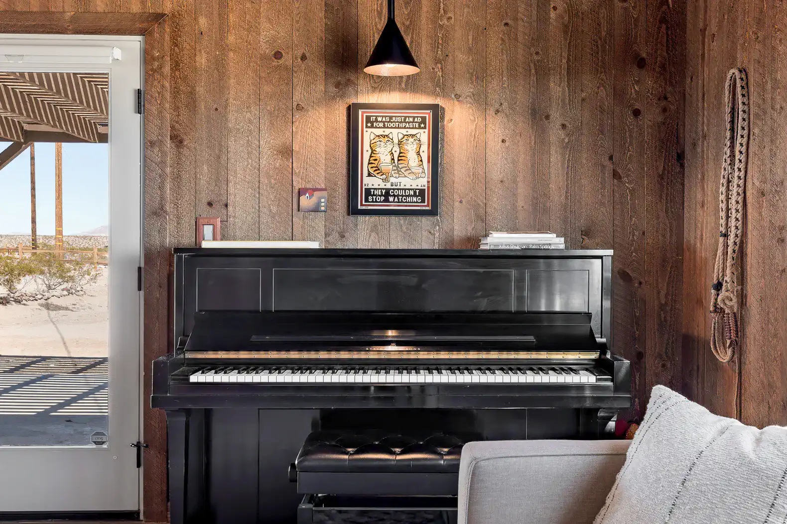 Cozy corner with a black piano against wooden walls and a view of the outdoors