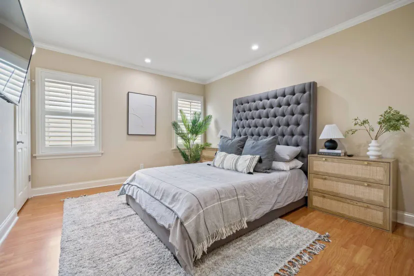 Gemütliches Hauptschlafzimmer mit einem großen Bett, dekorativen Kissen und natürlichem Licht