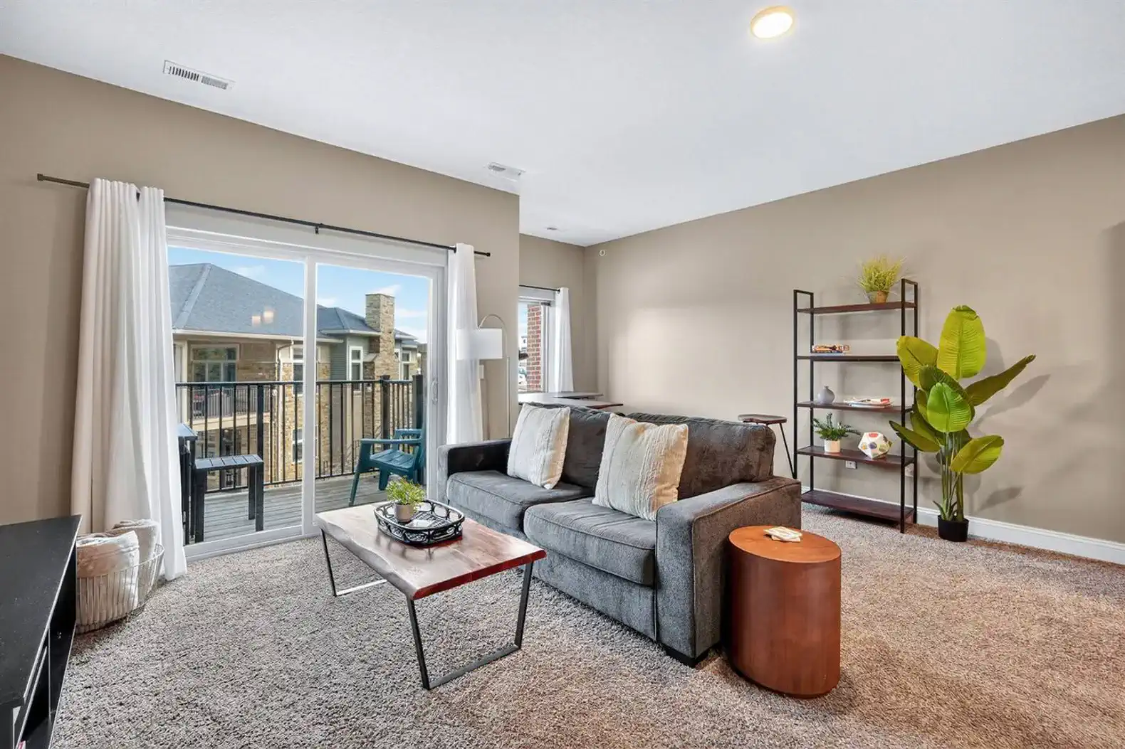 Cozy yet open, this living room connects seamlessly to the balcony and dining nook. A comfy sofa, warm accents, and modern shelving create a perfect mix of relaxation and function.