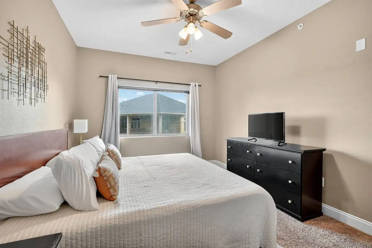Another view of the calming king suite—neutral tones, plush bedding, and a flat-screen TV at the foot of the bed. A tranquil retreat designed for restful nights and peaceful mornings.