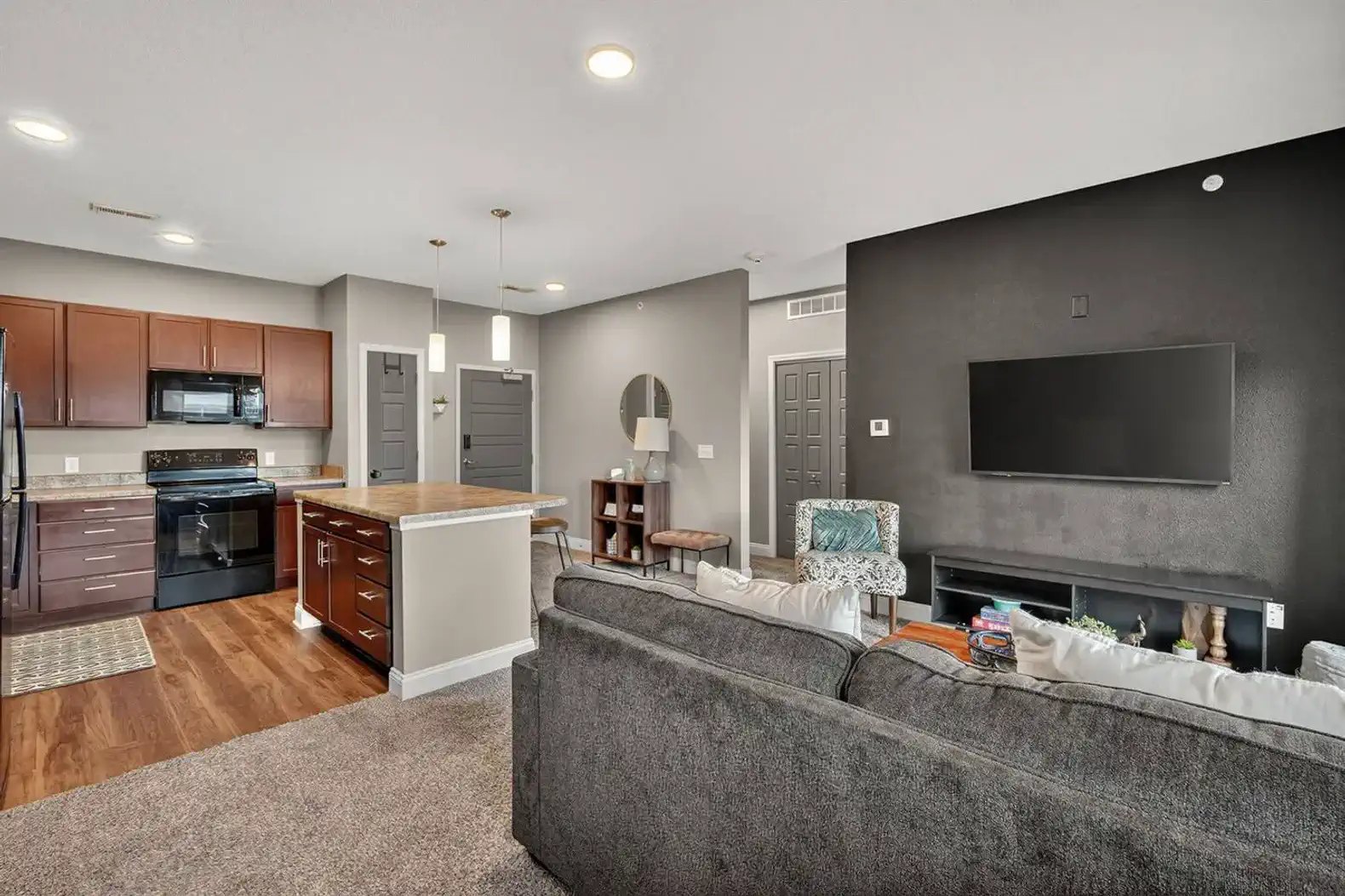 Bright, modern kitchen with full-size appliances and ample counter space. Pendant lights highlight the central island, perfect for coffee, cocktails, or casual meals. Convenient entryway adds