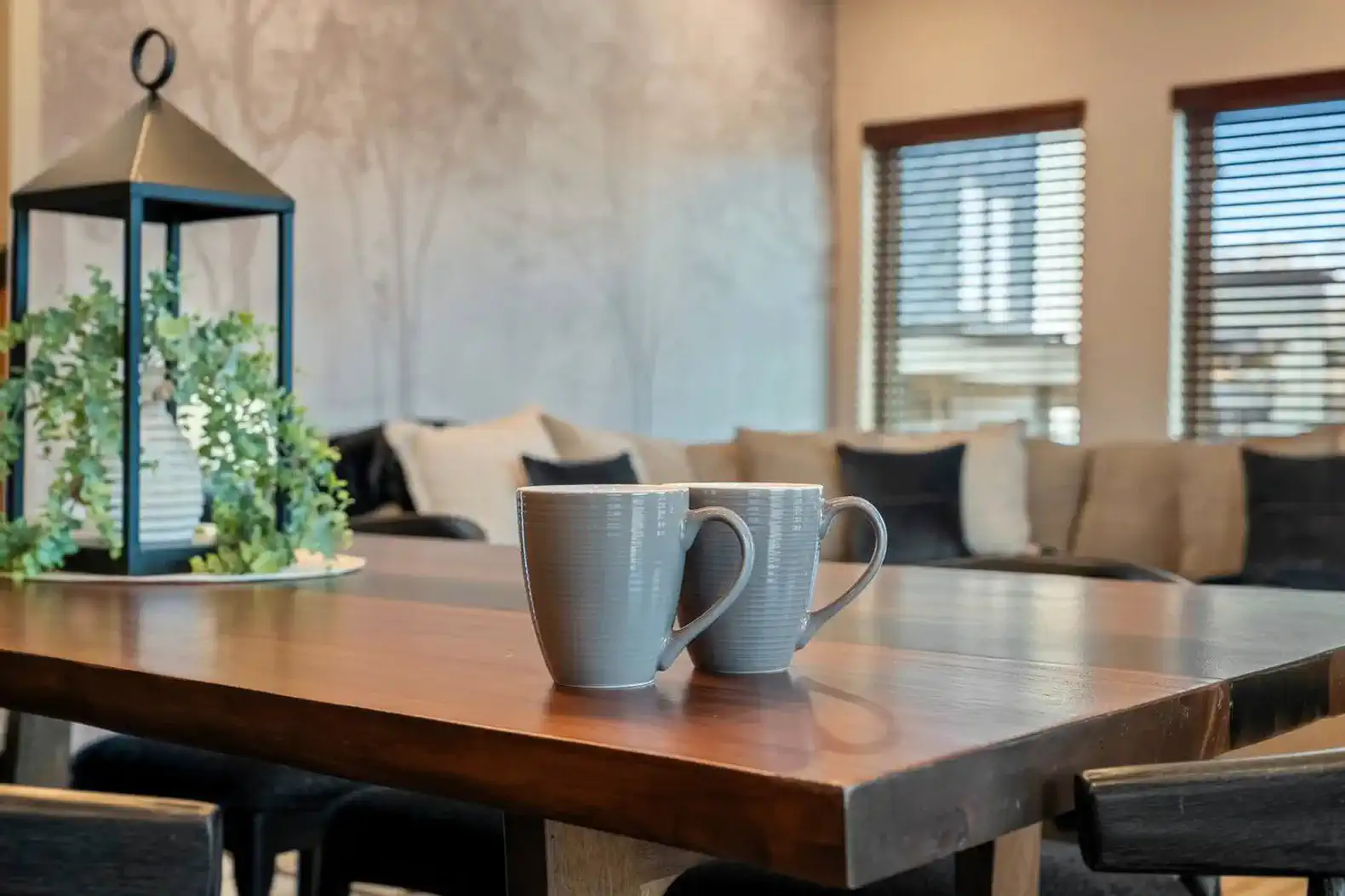 Cozy dining area with a wooden table, two mugs, and a view of the living room