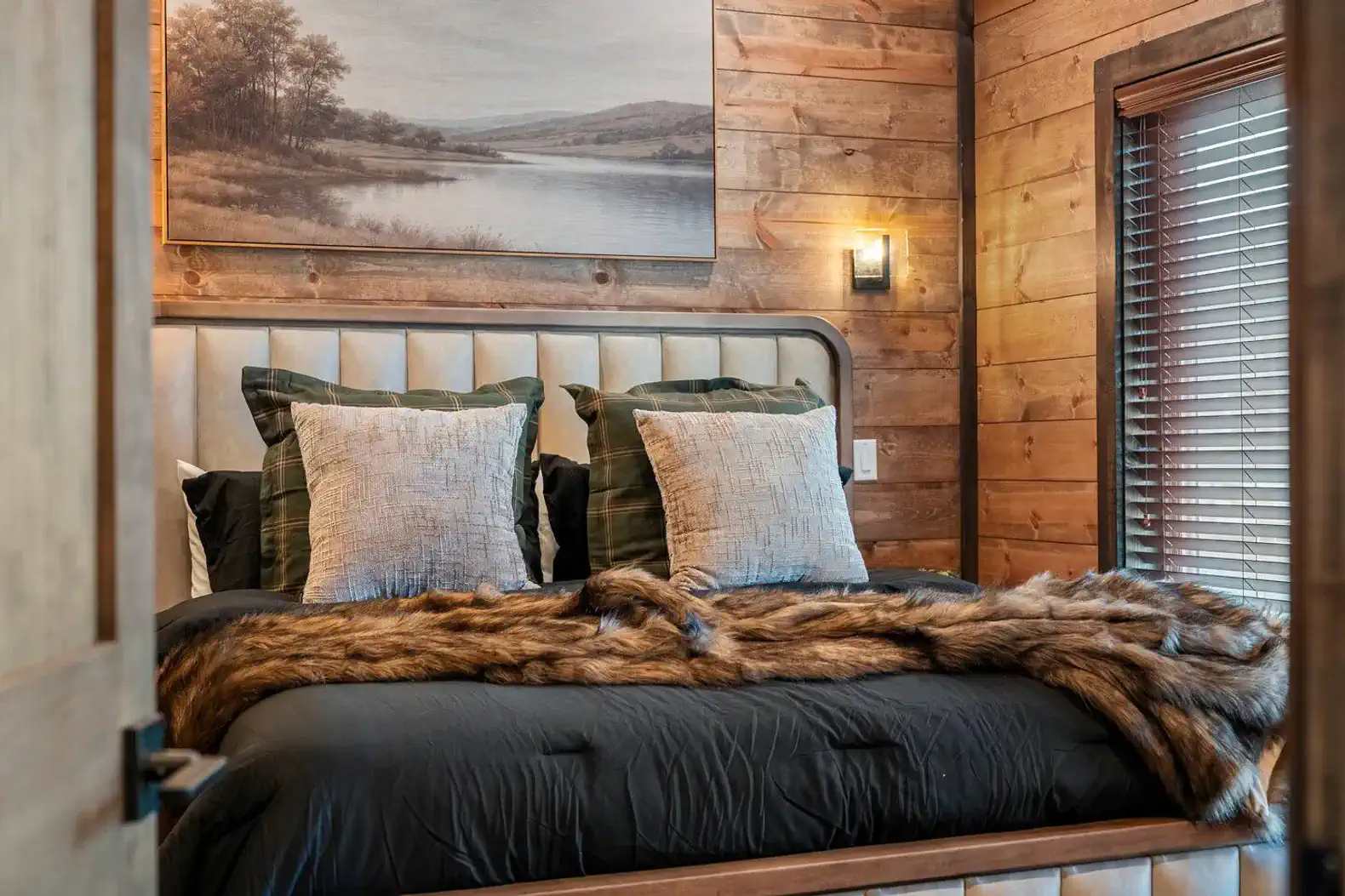 Cozy master bedroom with a plush bed, decorative pillows, and rustic wooden walls