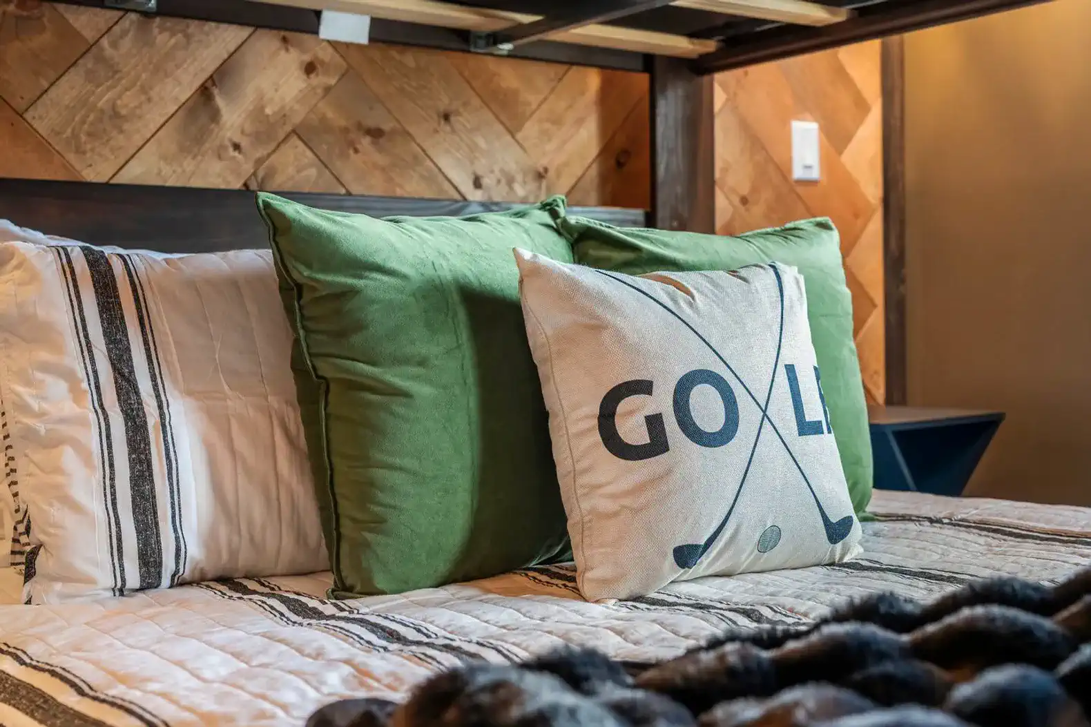 Cozy bedding with golf-themed pillows and textured headboard