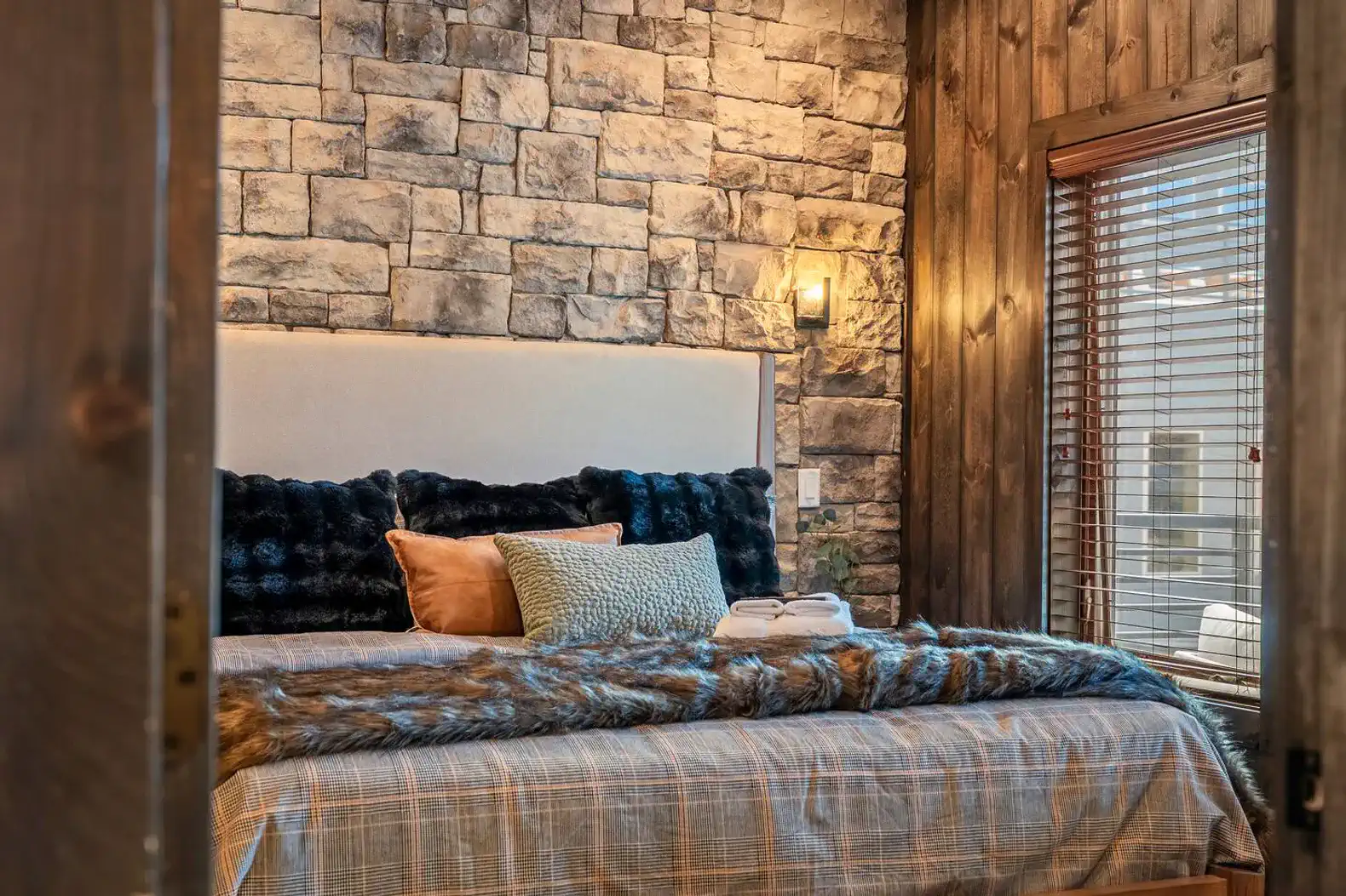 Cozy master bedroom with stone accent wall and plush bedding