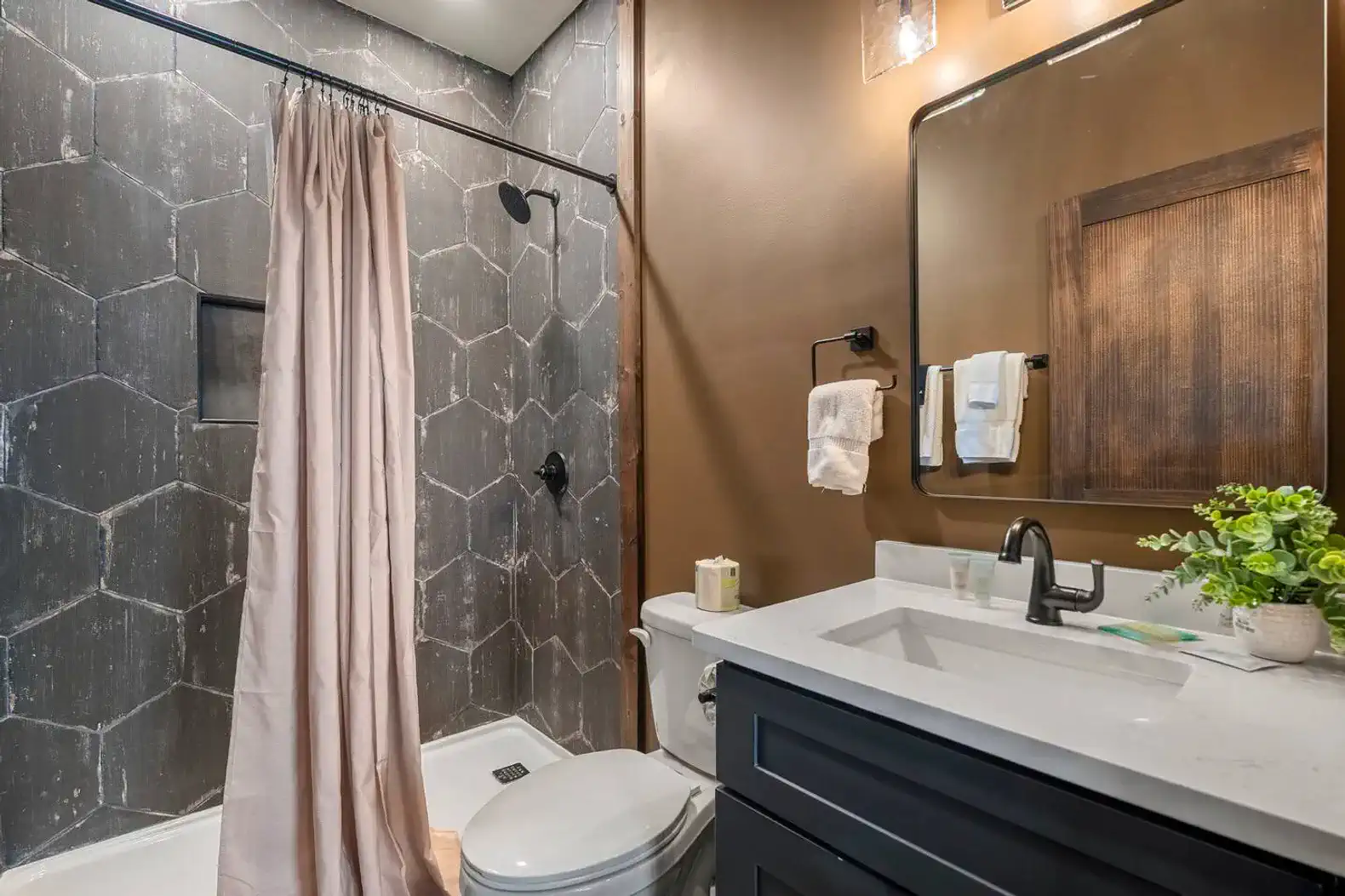 Stylish bathroom featuring a hexagonal tile wall, modern fixtures, and a shower with a curtain