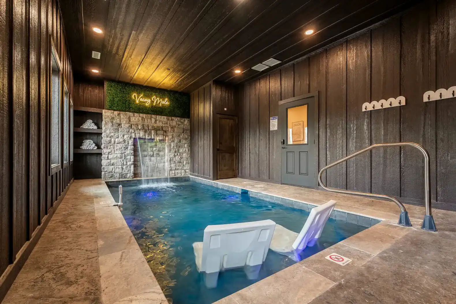 Indoor pool area with seating and waterfall feature