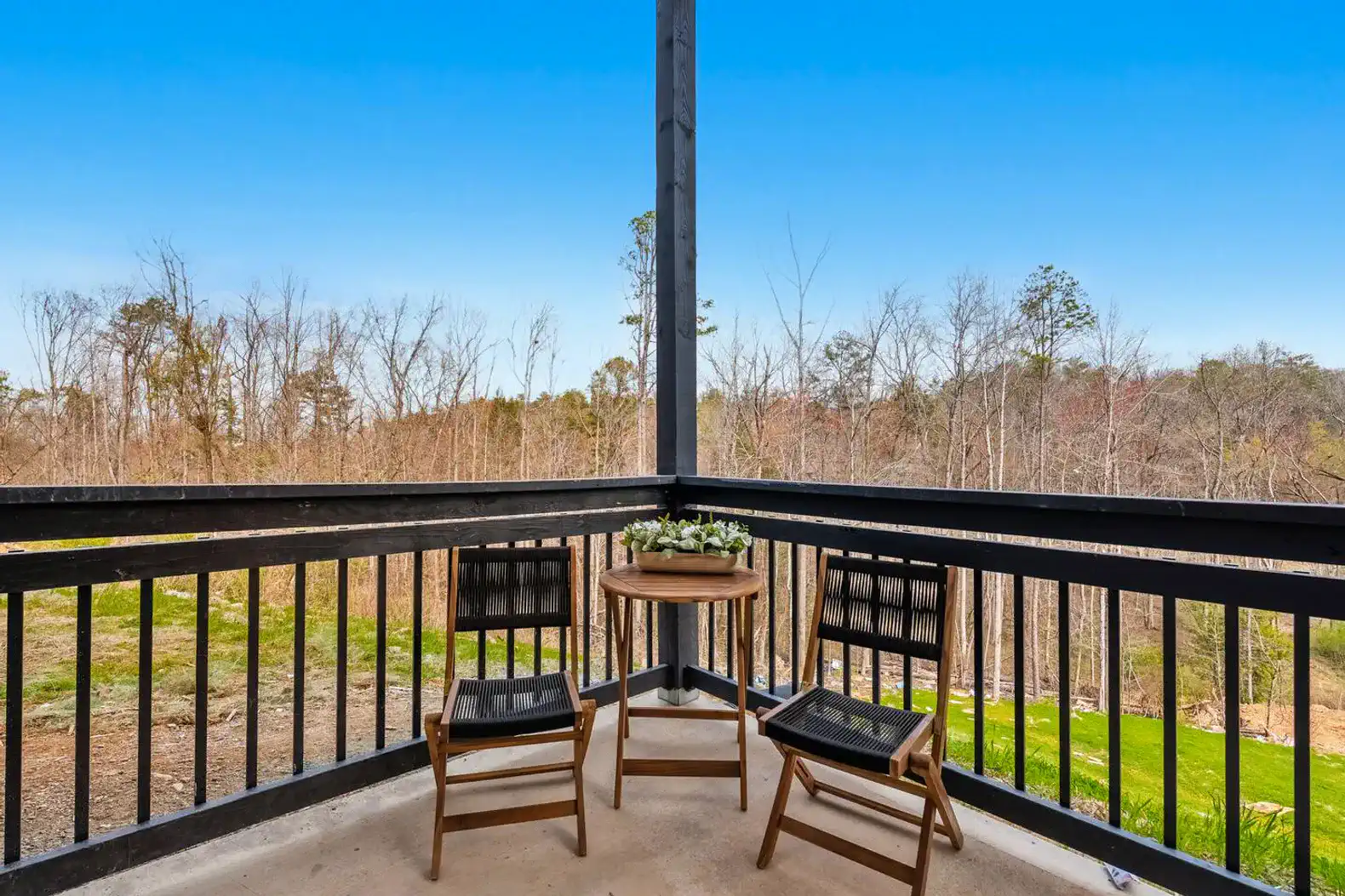Cozy balcony with two chairs and a small table overlooking a wooded area