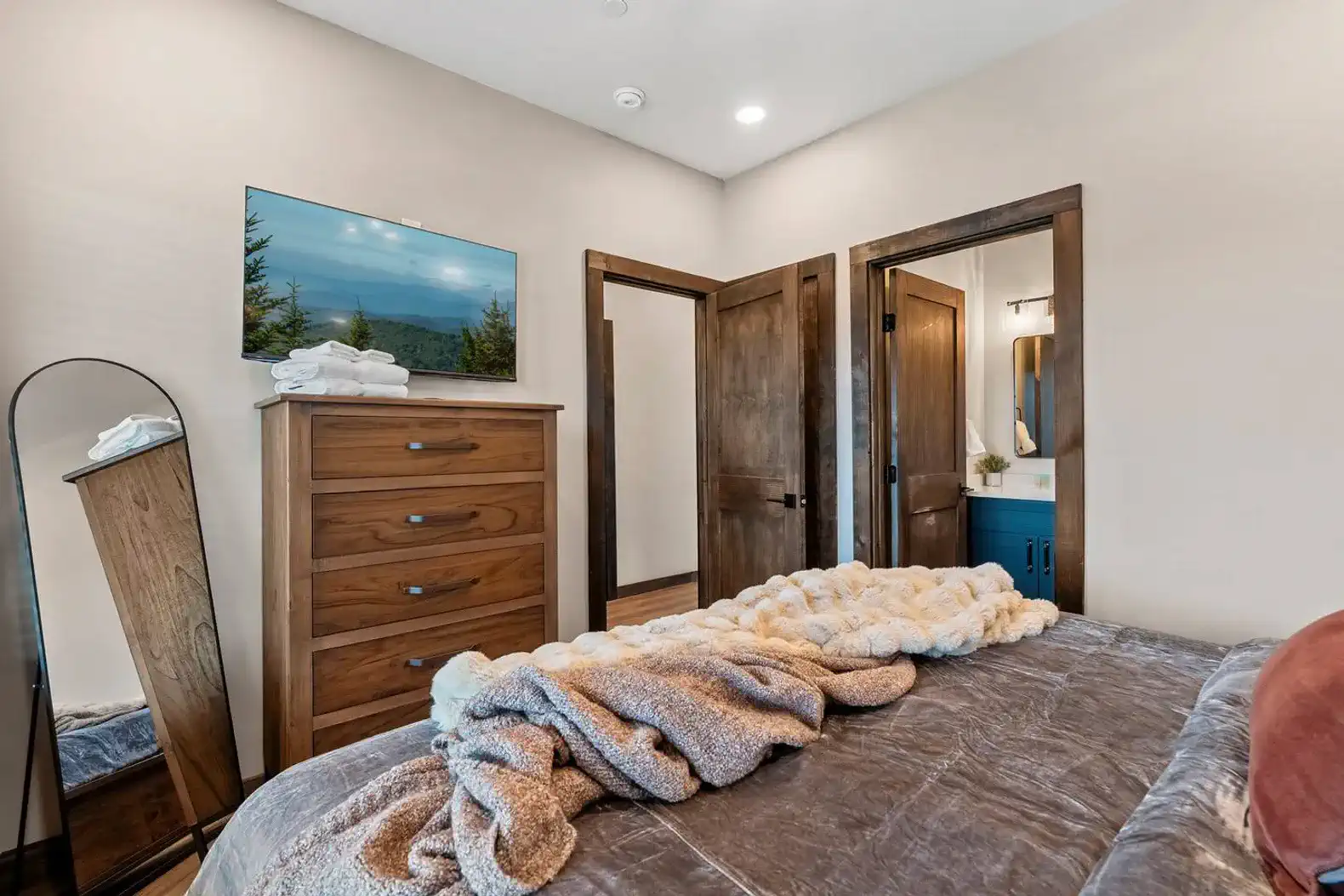 Cozy bedroom with a dresser, TV, and soft bedding