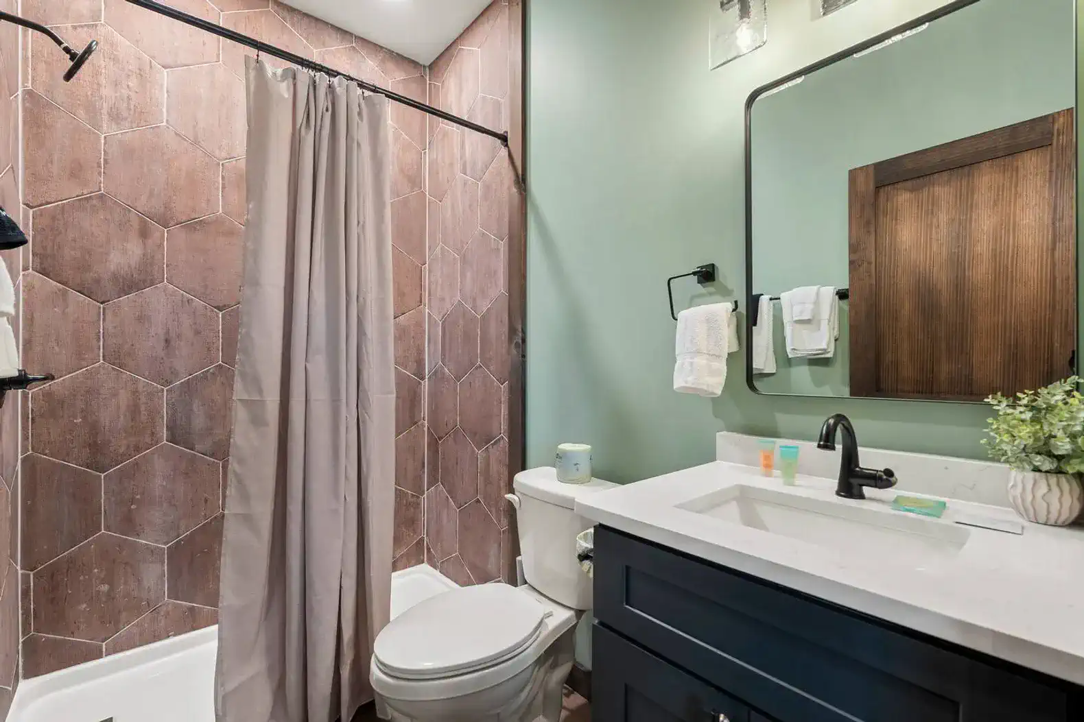 Stylish bathroom featuring hexagon tile, modern fixtures, and a shower curtain