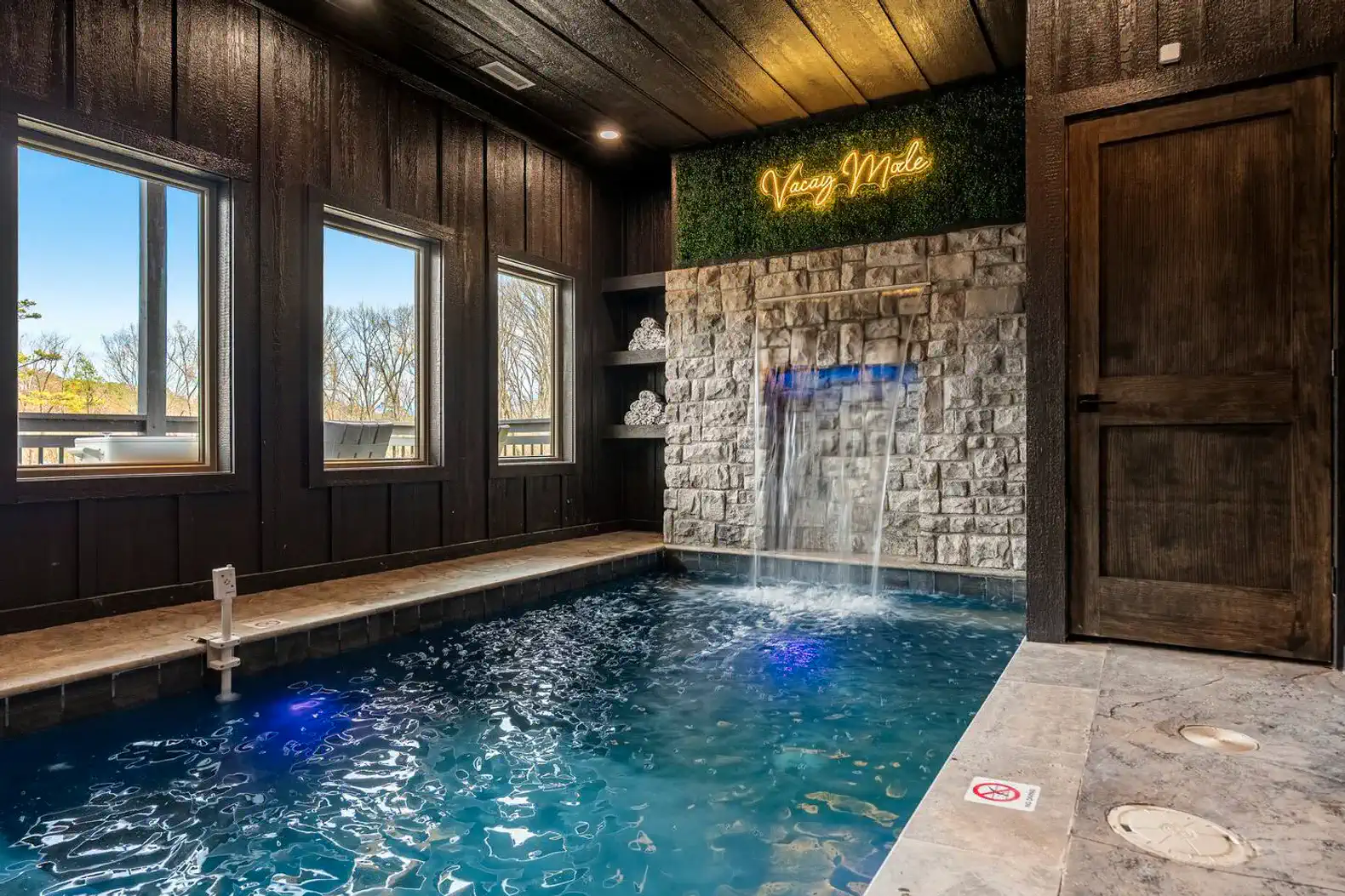 Indoor pool with waterfall feature and ambient lighting