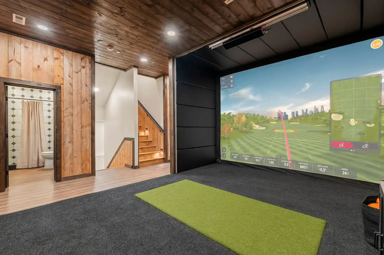 Indoor golf simulator area with a large screen and putting green