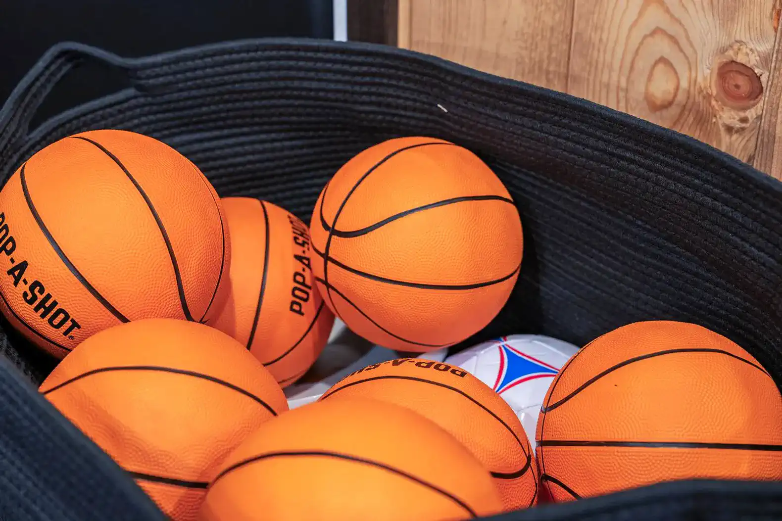 A collection of orange basketballs in a black basket