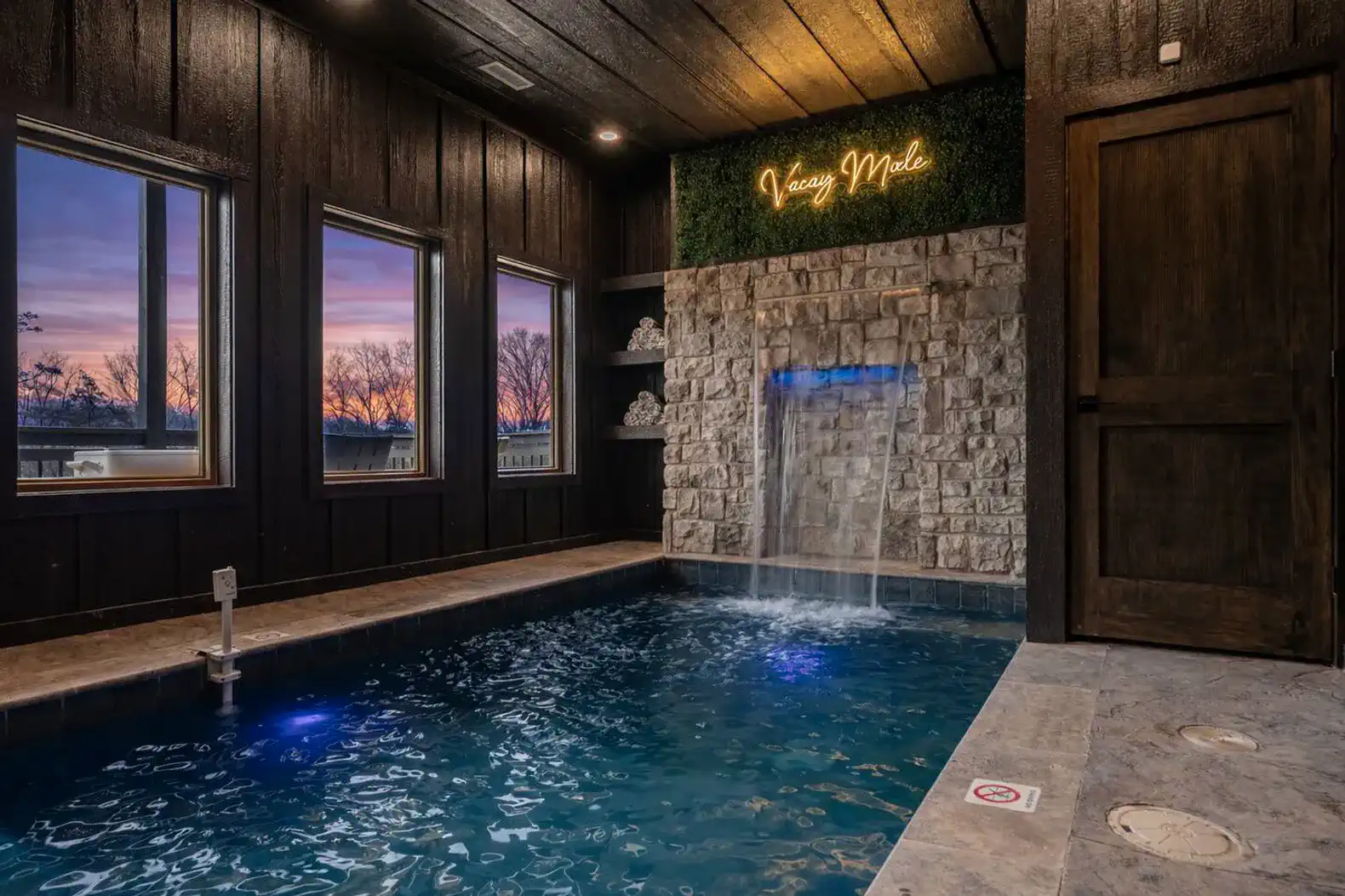Indoor pool with waterfall feature and evening sunset view