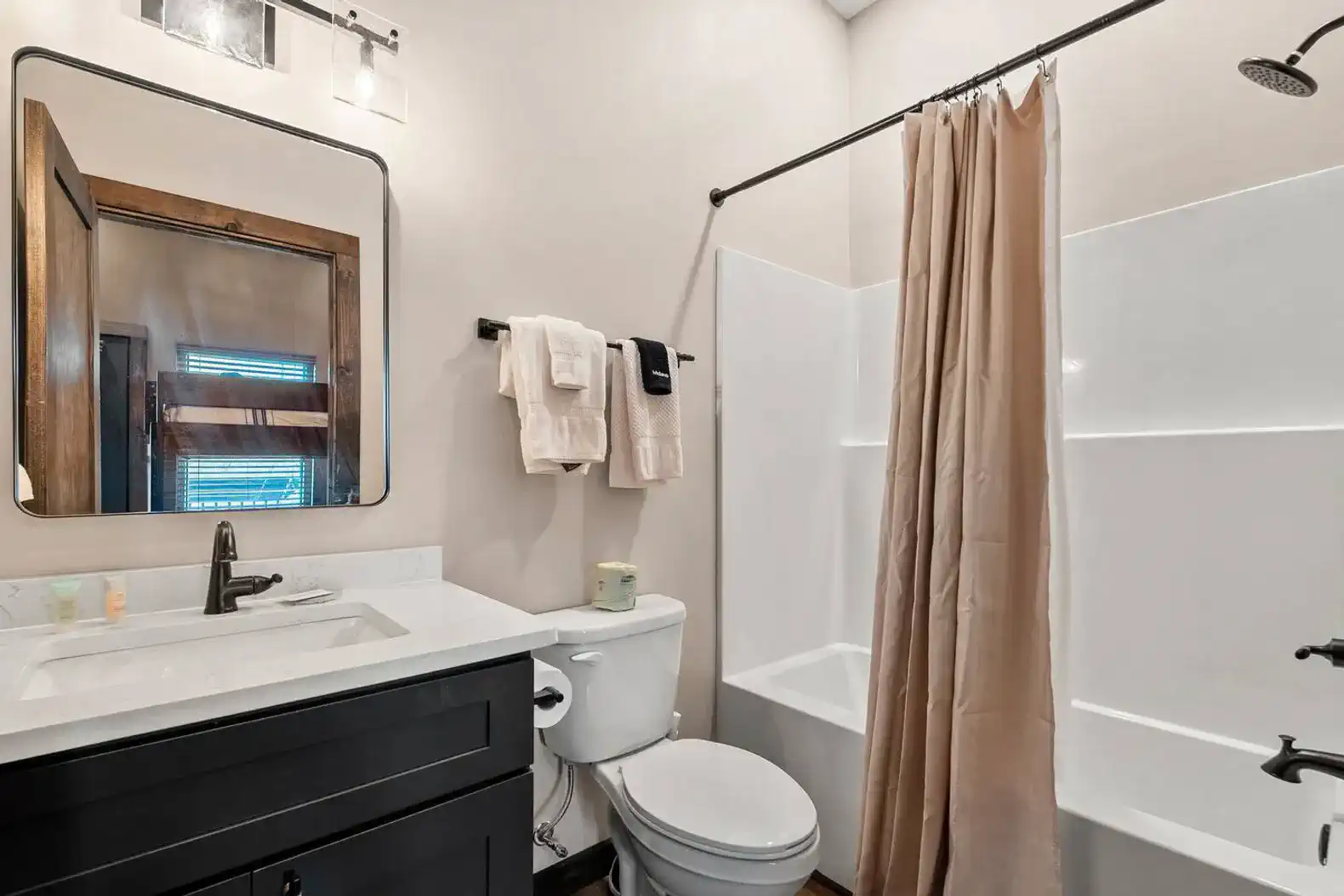 Modern bathroom with a dark vanity, white tub, and shower curtain