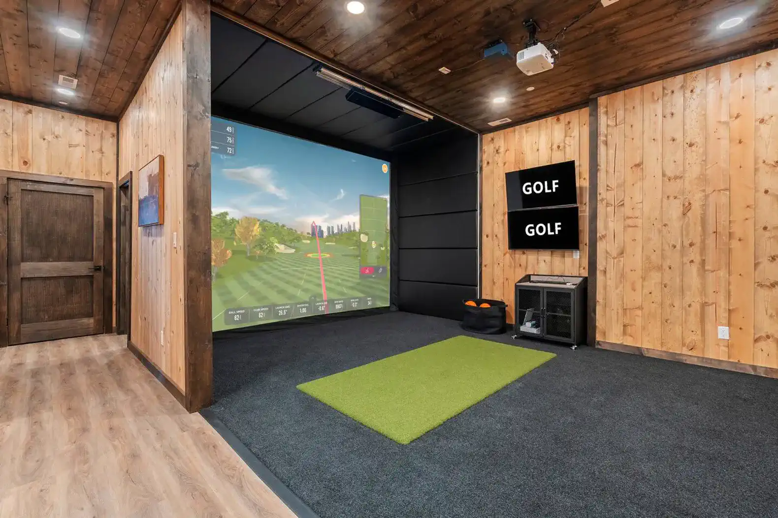 Indoor golf simulator with a large screen and putting green