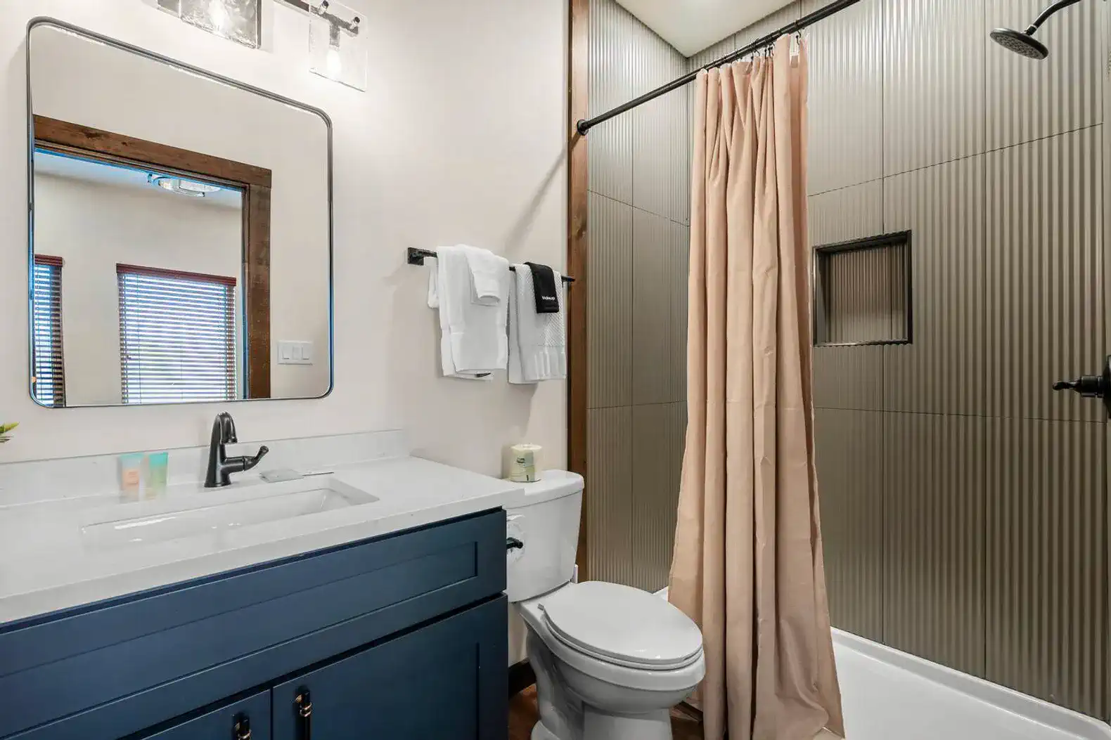 Modern bathroom with a blue vanity, shower curtain, and stylish fixtures