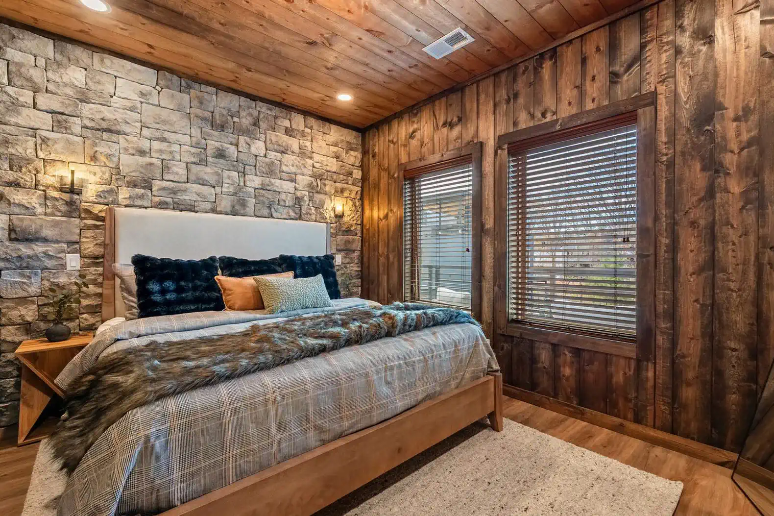 Cozy master bedroom with stone accent wall and large windows