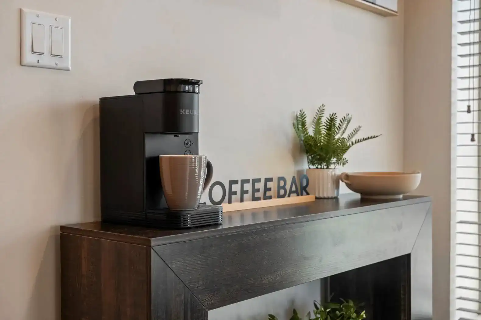Coffee bar setup with a coffee machine and mug on a wooden console table