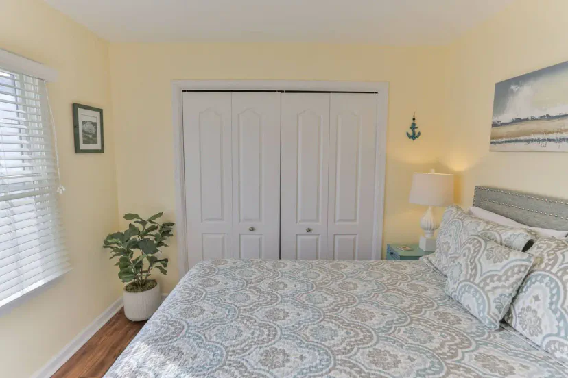 Acogedor dormitorio con una cama queen, paredes de color amarillo claro y amplio espacio en el armario con puertas corredizas