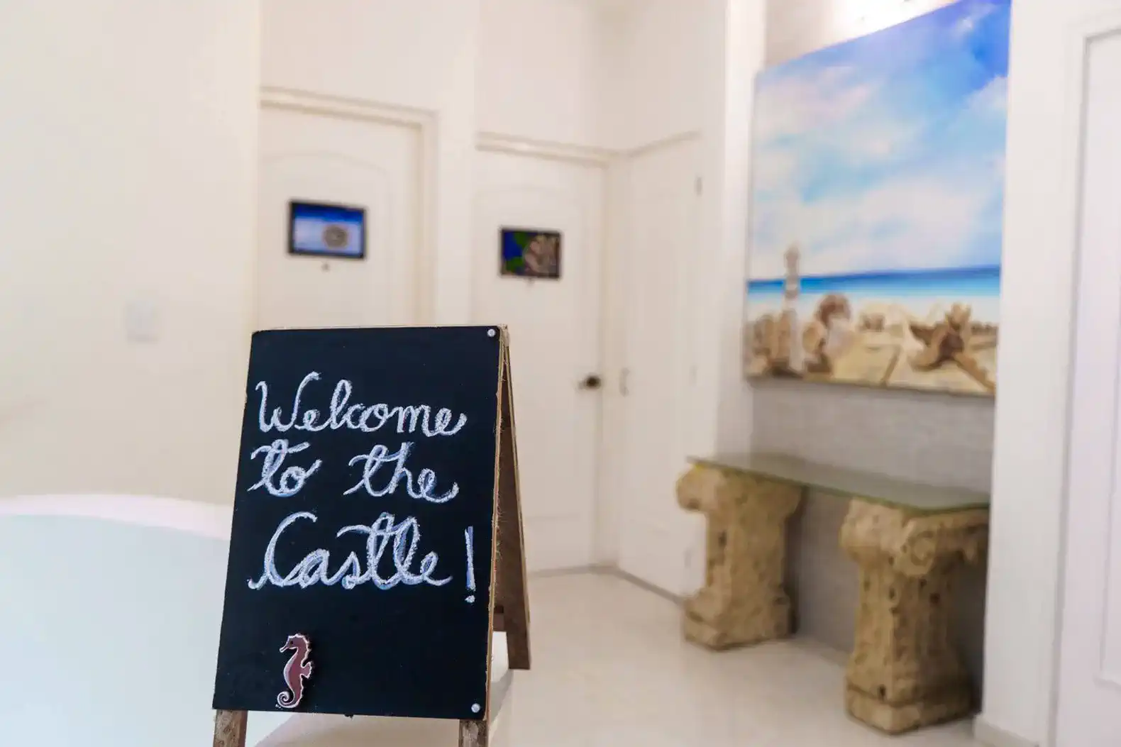 Welcoming sign inside the entrance with coastal artwork and decorative stone tables