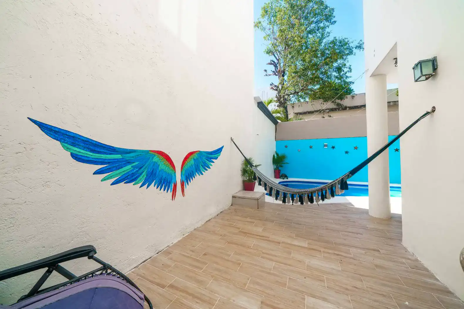 Colorful mural of wings beside a hammock in a bright outdoor space