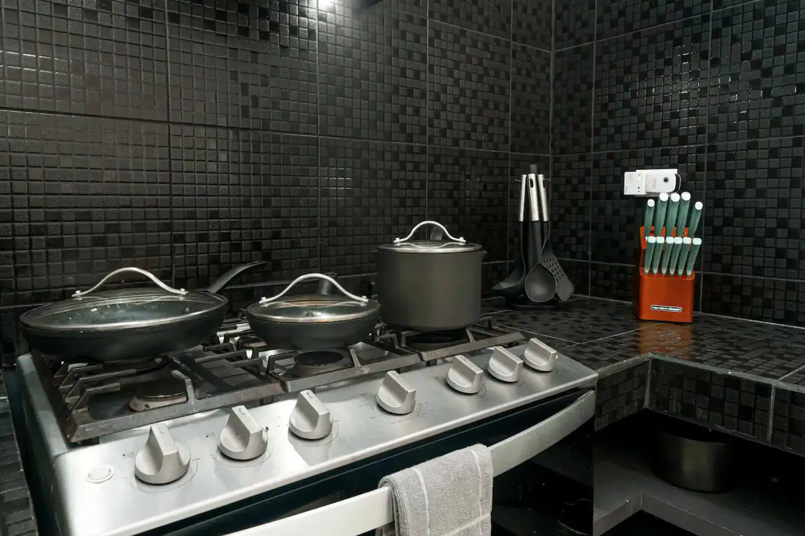 Modern kitchen with black tiled walls and stainless steel appliances
