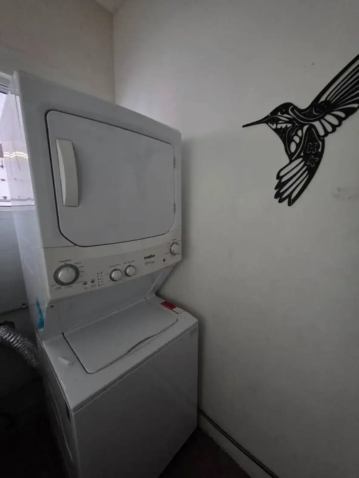 Stacked washer and dryer in a laundry area with a decorative wall art