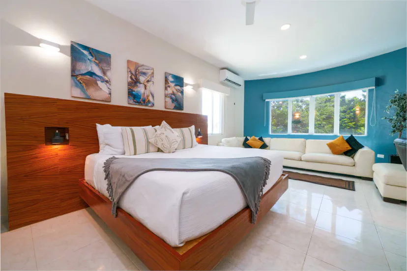 Bright king bedroom with stylish lounge area and lush garden views